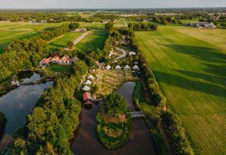 Vista aerea del parco vacanze REBL Outdoor in Frisia, Paesi Bassi, con tende, stagni e campi verdi intorno.