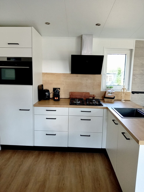 Cocina blanca moderna con encimeras de madera en Forest Lodge De Mooie Plek, Bospark Markelo, Países Bajos.