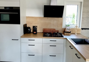 Cocina blanca moderna con encimeras de madera en Forest Lodge De Mooie Plek, Bospark Markelo, Países Bajos.