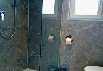 Salle de bain moderne avec douche, toilettes et fenêtre au Forest Lodge De Mooie Plek, Bospark Markelo, Pays-Bas.