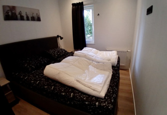 Gemütliches Schlafzimmer in der Forest Lodge De Mooie Plek, Bospark Markelo, Niederlande, mit Doppelbett.