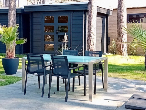 Terraza exterior con mesa y sillas modernas frente a Forest Lodge De Mooie Plek en Bospark Markelo, Países Bajos.