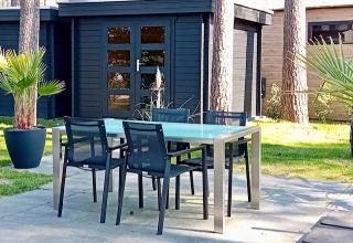 Patio esterno con tavolo e sedie moderne davanti a Forest Lodge De Mooie Plek a Bospark Markelo, Paesi Bassi.