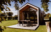 Casa pequeña moderna con terraza de madera en Holiday park Eigen Wijze, Países Bajos, rodeada de césped.