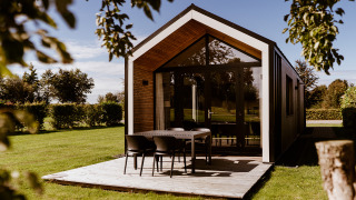 Casa pequeña moderna con terraza de madera en Holiday park Eigen Wijze, Países Bajos, rodeada de césped.