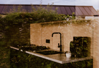 Reflection of greenery blending into a tiny house kitchen at Holiday park Eigen Wijze, Netherlands.