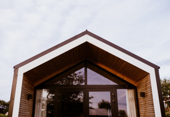 Casa pequeña moderna en Holiday park Eigen Wijze, Países Bajos, con fachada de madera y grandes ventanales.