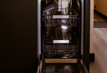 Open dishwasher in a tiny house at Holiday park Eigen Wijze in the Netherlands, with kettle and coffee maker on top.