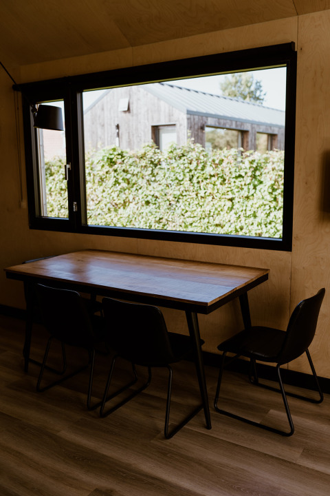 Eethoek in een tiny house bij Holiday park Eigen Wijze, Nederland, met tafel en groot raam.
