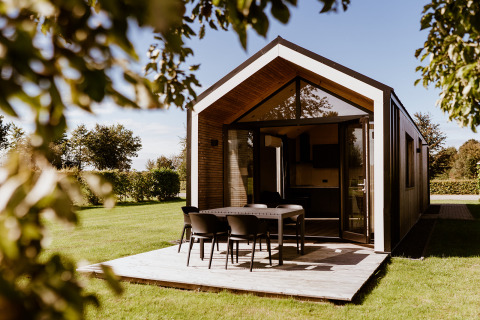 Casa pequeña moderna en Holiday park Eigen Wijze, Países Bajos, con terraza y zona de comedor exterior.