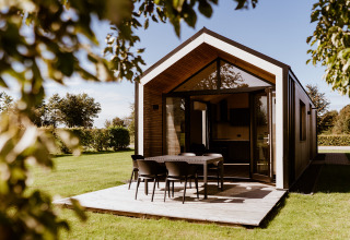 Moderne tiny house i Holiday park Eigen Wijze, Nederlandene, med terrasse og udendørs spiseplads.