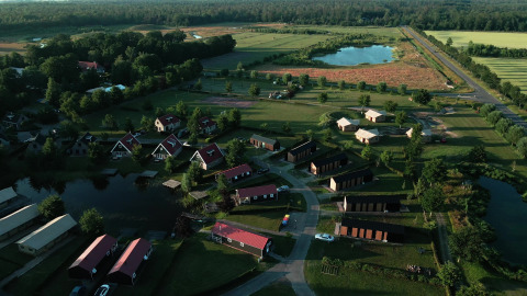 Vista aérea de una tiny house en Holiday park Eigen Wijze, Países Bajos, rodeada de campos verdes y lagunas.