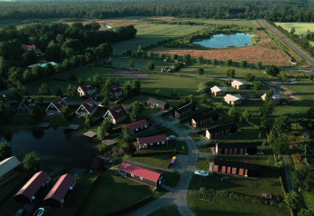 Vista aérea de una tiny house en Holiday park Eigen Wijze, Países Bajos, rodeada de campos verdes y lagunas.