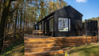Koya Tiny Cabin ved Wilsumer Berge i Tyskland, sort træhytte med terrasse omgivet af skov og natur.