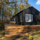 Koya Tiny Cabin ved Wilsumer Berge i Tyskland, sort træhytte med terrasse omgivet af skov og natur.
