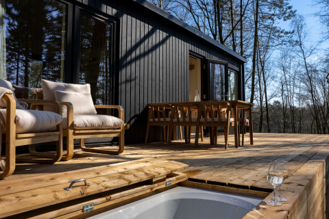 Terrasse der Koya Tiny Cabin mit Holzmöbeln und Waldblick bei Wilsumer Berge, Deutschland.