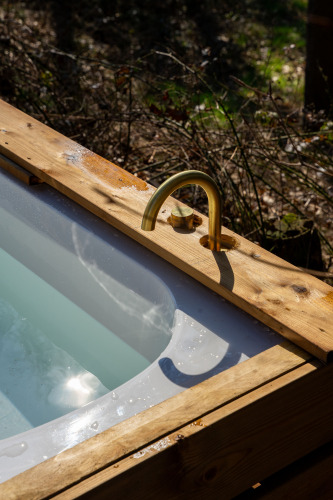 Outdoor bathtub with brass faucet and wooden trim at Koya Tiny Cabin, Wilsumer Berge, Germany.