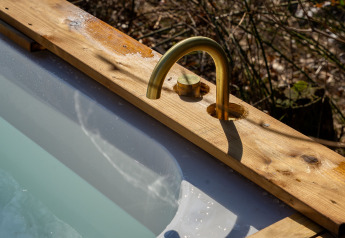 Vasca da bagno all'aperto con rubinetto in ottone e bordo in legno presso Koya Tiny Cabin a Wilsumer Berge, Germania.