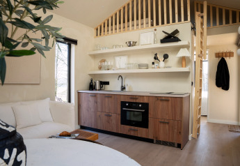 Moderne compacte keuken in Koya Tiny Cabin bij Wilsumer Berge, Duitsland, met houtaccenten en slaapzolder.