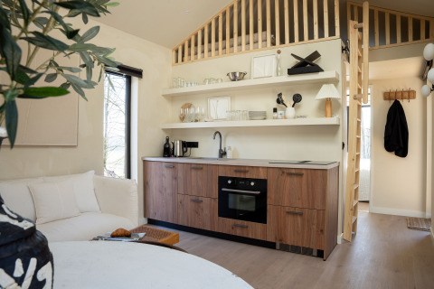 Cucina moderna e compatta nella Koya Tiny Cabin al Wilsumer Berge, Germania, con dettagli in legno e soppalco.