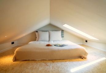 Knusse slaapkamer in Koya Tiny Cabin bij Wilsumer Berge, Duitsland, met laag schuin dak en modern interieur.