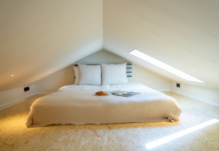 Hyggeligt soveværelse i Koya Tiny Cabin på Wilsumer Berge, Tyskland, med lavt loft og moderne indretning.