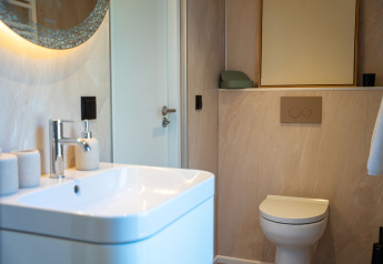 Bagno moderno nella Koya Tiny Cabin a Wilsumer Berge, Germania, con lavandino, WC e specchio.