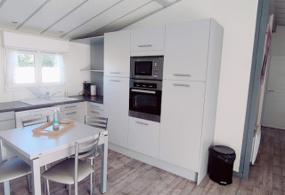 Moderne Küche und Essbereich in einer CRL 1/5 Pers. Lodge auf Camping Seasonova Les Vosges du Nord in Frankreich.