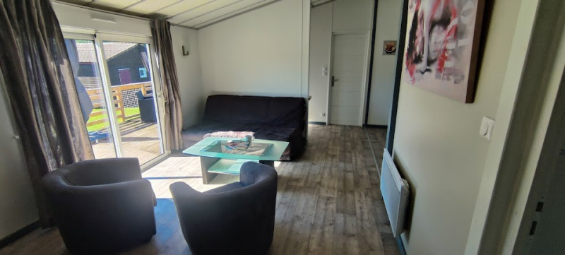 Woonkamer van een lodge op Camping Seasonova Les Vosges du Nord met bank, stoelen en terraszicht.