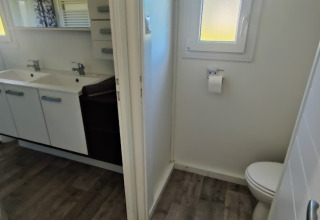 Badeværelse og toilet i en lodge på Camping Seasonova Les Vosges du Nord, med dobbelt håndvask og vindue.