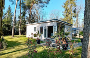 Forest Lodge De Mooie Plek ved Bospark Markelo i Holland, omgivet af træer og et grønt græsareal.
