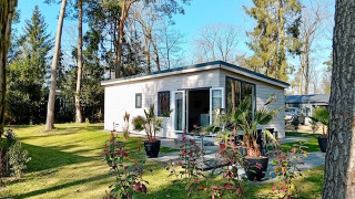 Forest Lodge De Mooie Plek bij Bospark Markelo in Nederland, omgeven door bomen en een groen gazon.