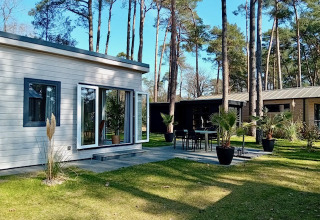 Forest Lodge De Mooie Plek presso Bospark Markelo nei Paesi Bassi, casa moderna e terrazza tra alberi alti.