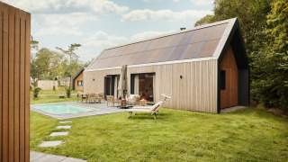 Foto de un lodge moderno con grandes paneles solares en el techo, piscina y patio amueblado rodeado de césped.