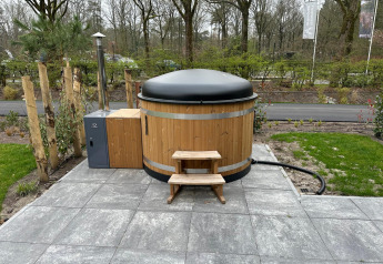Beheizter Whirlpool mit Holzverkleidung und Stufen bei Essenburgh im Veluwepark de Bosgraaf, Niederlande.