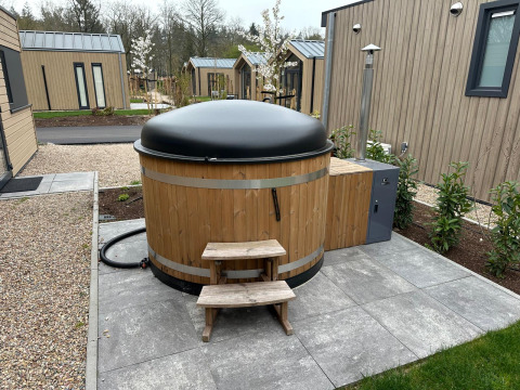 Bubbelbad met zwart deksel bij lodge Essenburgh in Veluwepark de Bosgraaf, Nederland, buiten geplaatst.