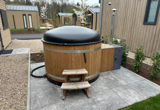 Jacuzzi exterior con tapa negra en la cabaña Essenburgh en Veluwepark de Bosgraaf, Países Bajos.