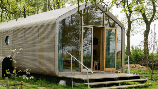 Wrap house lodge with sauna and bathtub at Resort de Parel, Netherlands, surrounded by lush greenery.