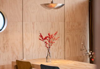 Comedor moderno con sillas coloridas e interior de madera en Wrap house con sauna en Resort de Parel, Países Bajos.
