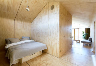 Dormitorio y sala modernos de madera en Wrap house con sauna y bañera en Resort de Parel, Países Bajos.