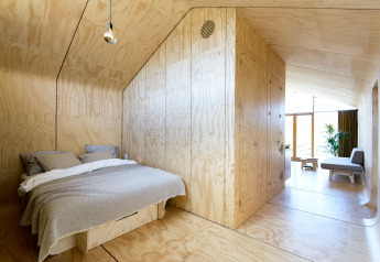 Camera da letto moderna in legno e soggiorno nella Wrap house con sauna al Resort de Parel, Paesi Bassi.