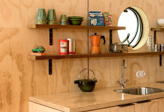 Estantes de cocina modernos y fregadero en Wrap House con objetos retro y espejo circular en la pared.