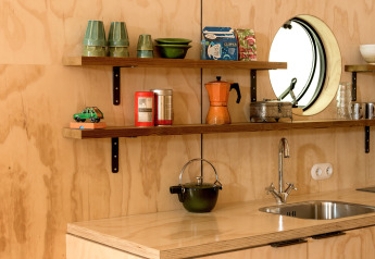 Mensole da cucina moderne con oggetti vintage, specchio tondo e lavello nel Wrap House al Resort de Parel.