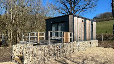 Moderna tiny house en Kohnenhof, Luxemburgo, con revestimiento de madera y terraza en entorno natural.