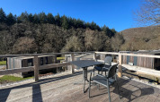 Zicht vanaf houten terras met tafel en twee stoelen bij Tiny House op Kohnenhof in Luxemburg, omringd door bos.