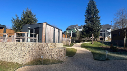 Casa tiny house moderna en Kohnenhof, Luxemburgo, rodeada de naturaleza y cielo azul claro en día soleado.