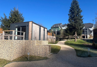 Casa tiny house moderna al Kohnenhof in Lussemburgo, immersa nel verde e sotto un cielo azzurro e limpido.