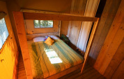 Schlafzimmer im Lodgetent Bordeaux auf La Draille in Frankreich mit Holzwänden und Doppelbett.