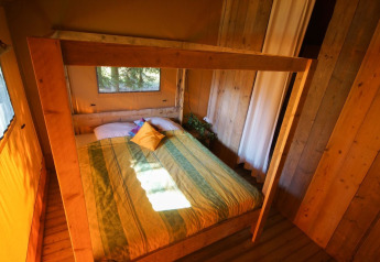 Schlafzimmer im Lodgetent Bordeaux auf La Draille in Frankreich mit Holzwänden und Doppelbett.