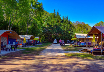 Safari tents at Lodgetent Bordeaux, La Draille, France, with green trees and a bright blue sky.